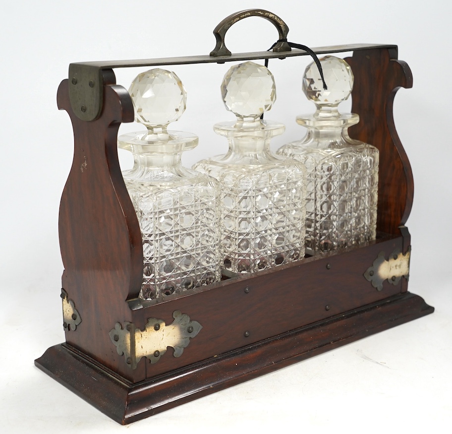 A three bottle tantalus with key, 38cm wide. Condition - fair, chipping to the stoppers